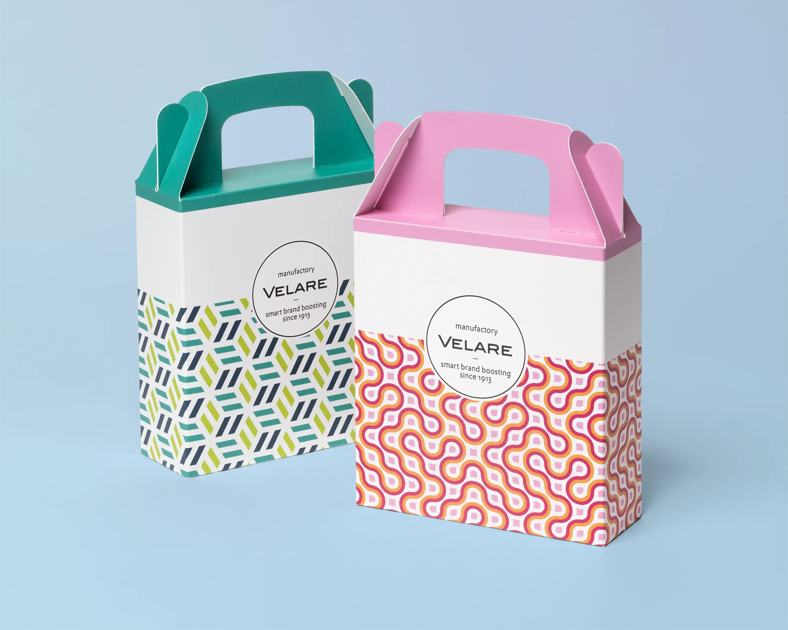 Giebelbox mit Tragegriff, zwei Verpackungen in gleicher Größe und unterschiedlichen Farben, blauer Hintergrund