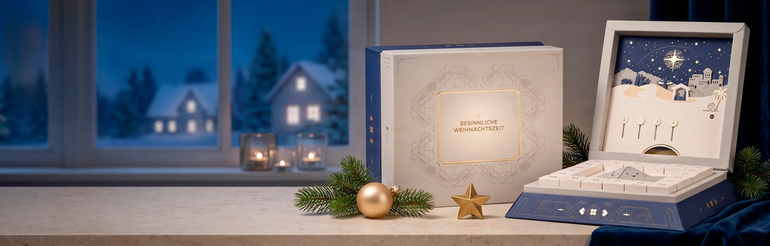 Ein Panorama-Produktbild auf einer Fensterbank, das eine weihnachtliche Verpackungskomposition zeigt. Mittig steht eine quadratische weiße Schachtel mit kunstvollen goldenen Linienmustern und der Aufschrift „BESINNLICHE WEIHNACHTSZEIT“. Rechts davon präse